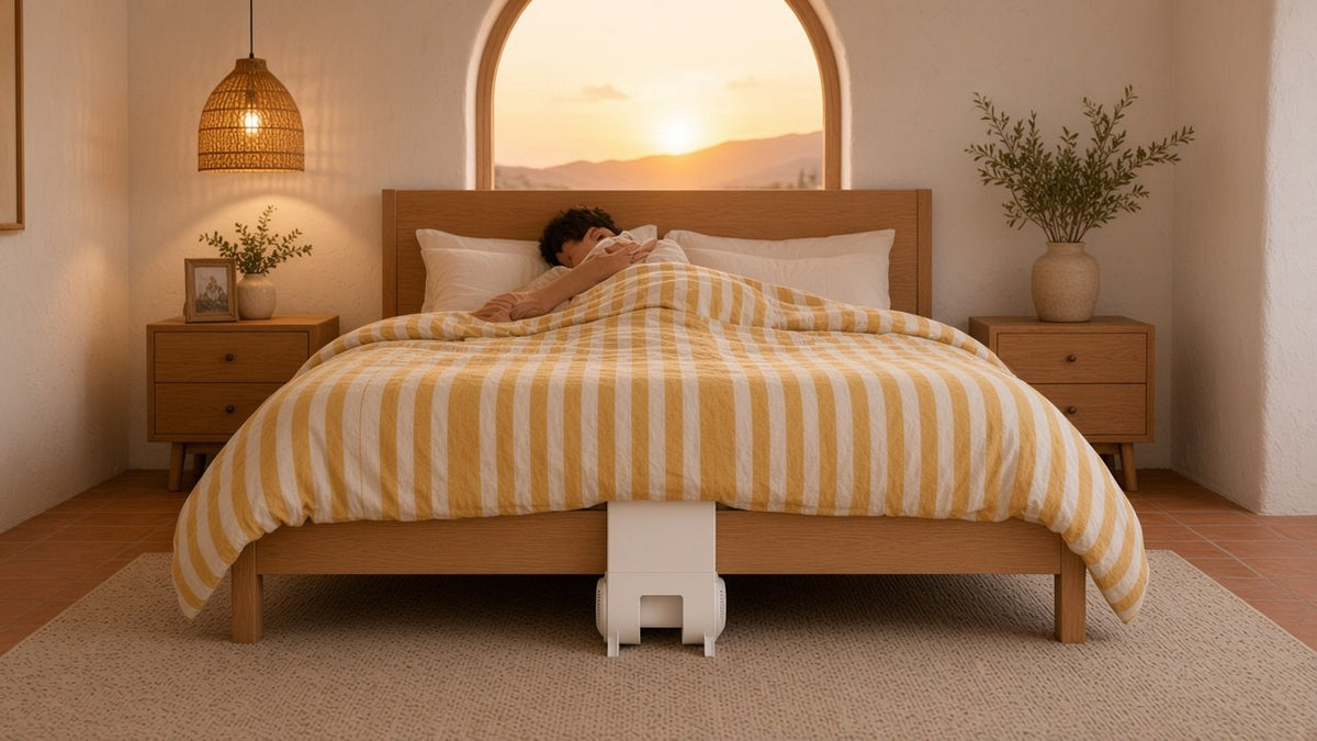 Desert modern bedroom at sunset with a man asleep and a bFan under bed fan centered at the foot of an oak bed