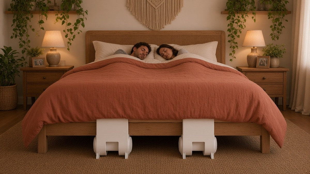 Couple asleep in a bohemian bedroom with two bFan under bed fans, one below each sleeper at the foot of the bed